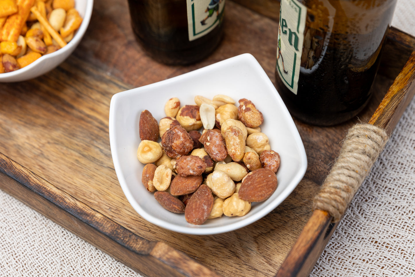Süßer griechischer Nussmix mit Erdnüssen, Mandeln, Haselnüssen, geröstetem Sesam und feinem Karamellüberzug in einer Keramikschale – mediterraner Snack aus hochwertigen Zutaten.